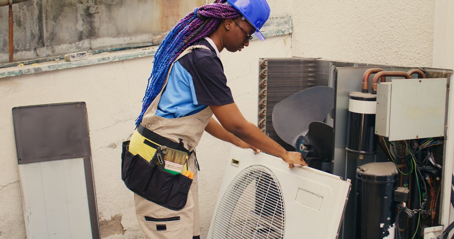 HVAC technician maintaining an AC unit for affordable AC replacement in Katy, TX, ensuring optimal cooling performance.