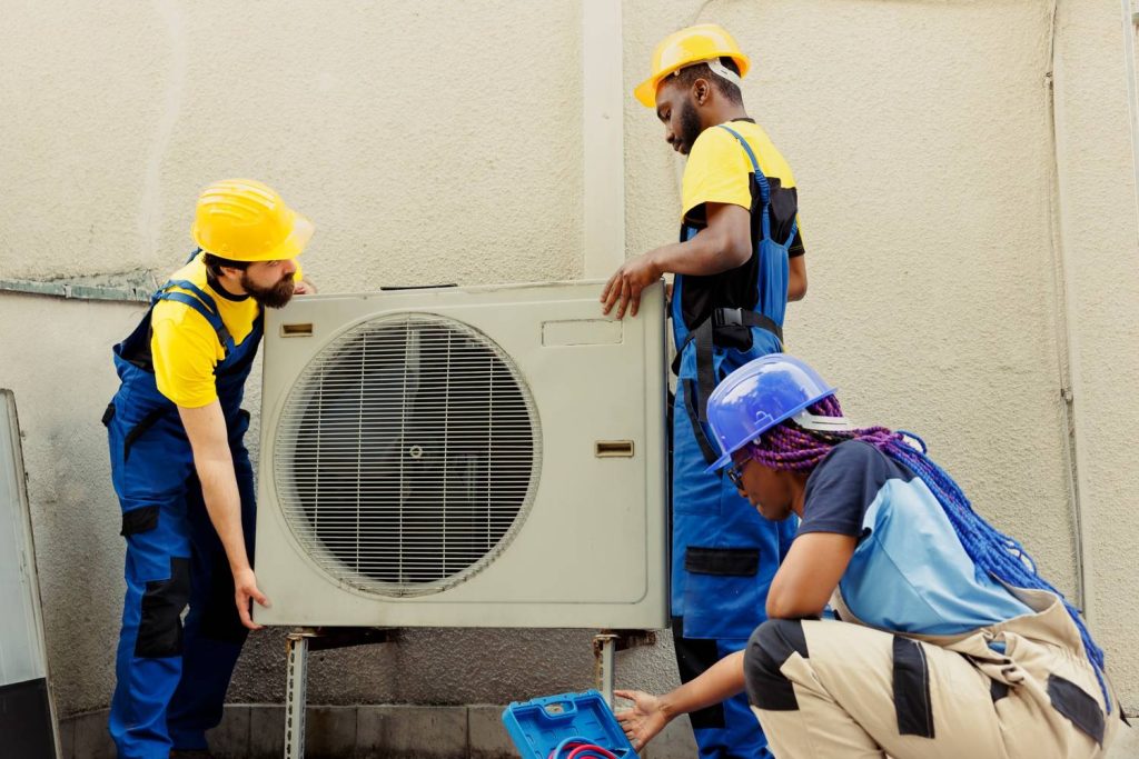 Diverse team of HVAC technicians performing affordable AC replacement in Katy, TX, on an outdoor unit for efficient cooling.