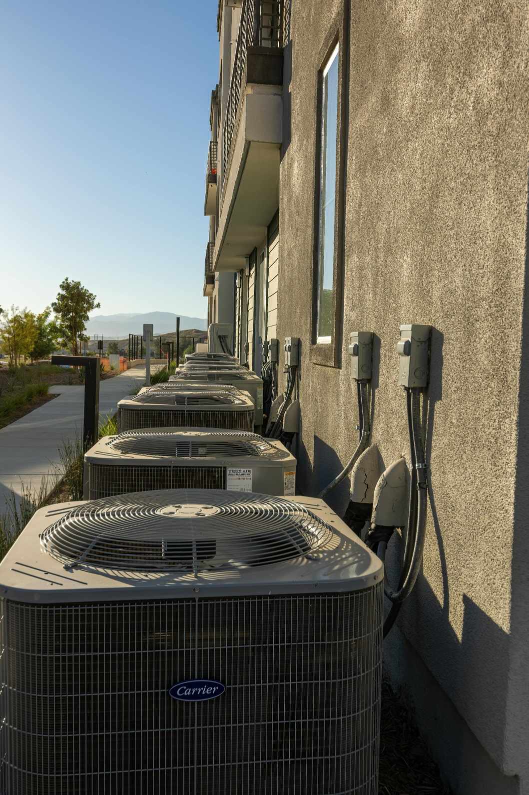 Row of Carrier AC units along a building, ideal for emergency AC repair near me in Katy, TX, ensuring reliable cooling.