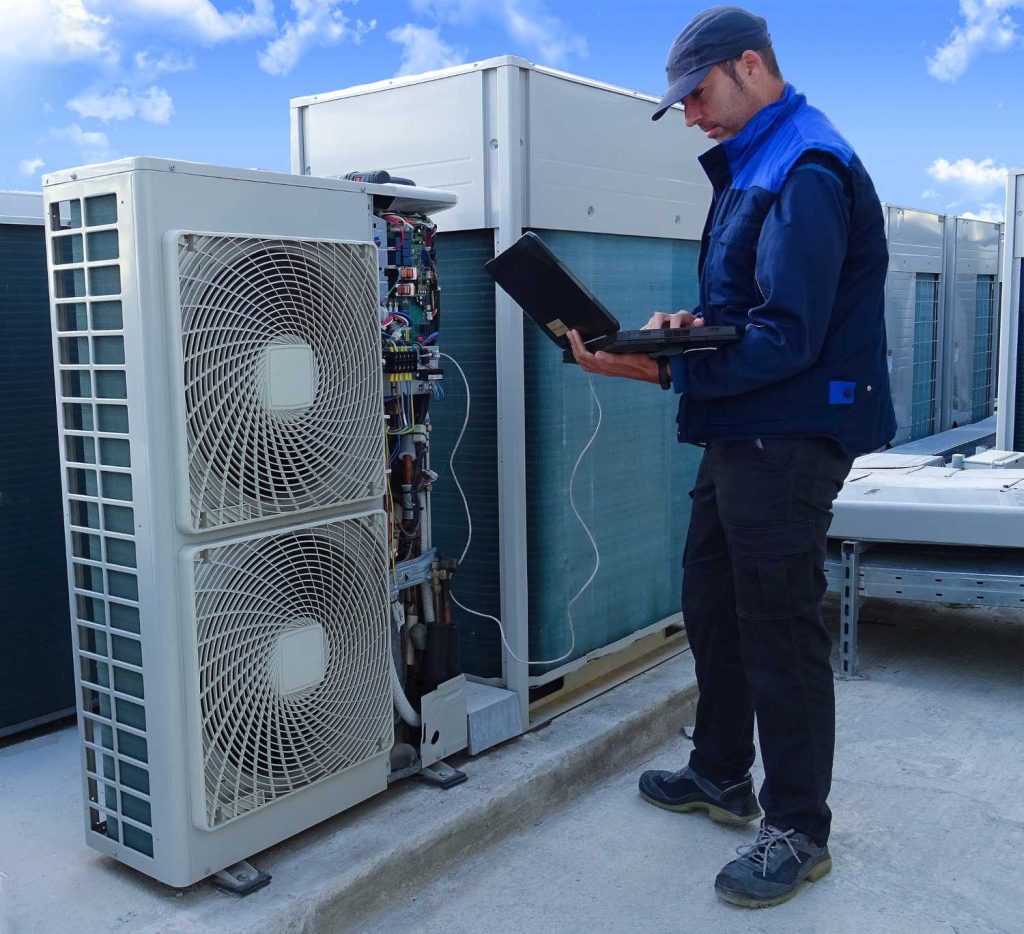 Technician using a laptop to install an AC unit on a rooftop, offering AC installation in Katy, TX.