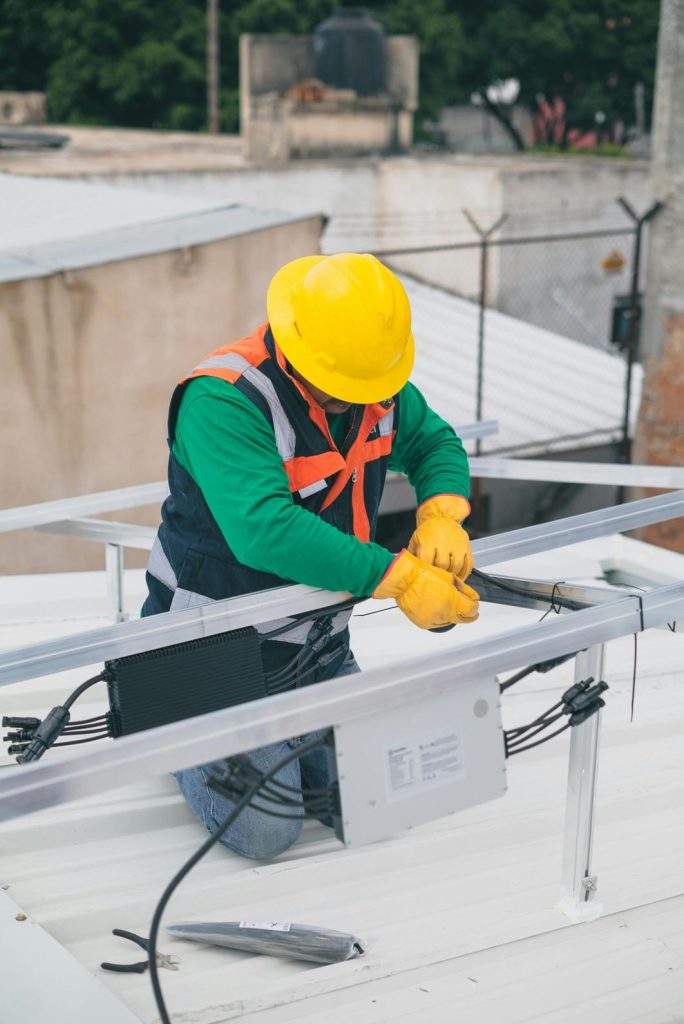 Skilled technician installing energy efficient AC unit on a rooftop in Katy TX, wearing safety gear and working with modern equipment.