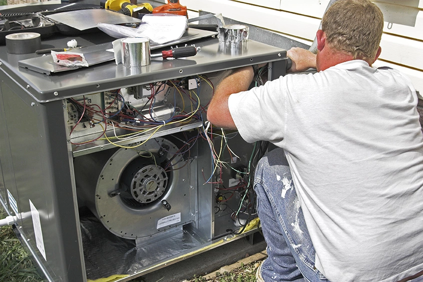 Technician repairing an AC unit with tools, highlighting energy efficient AC installation in Katy TX.