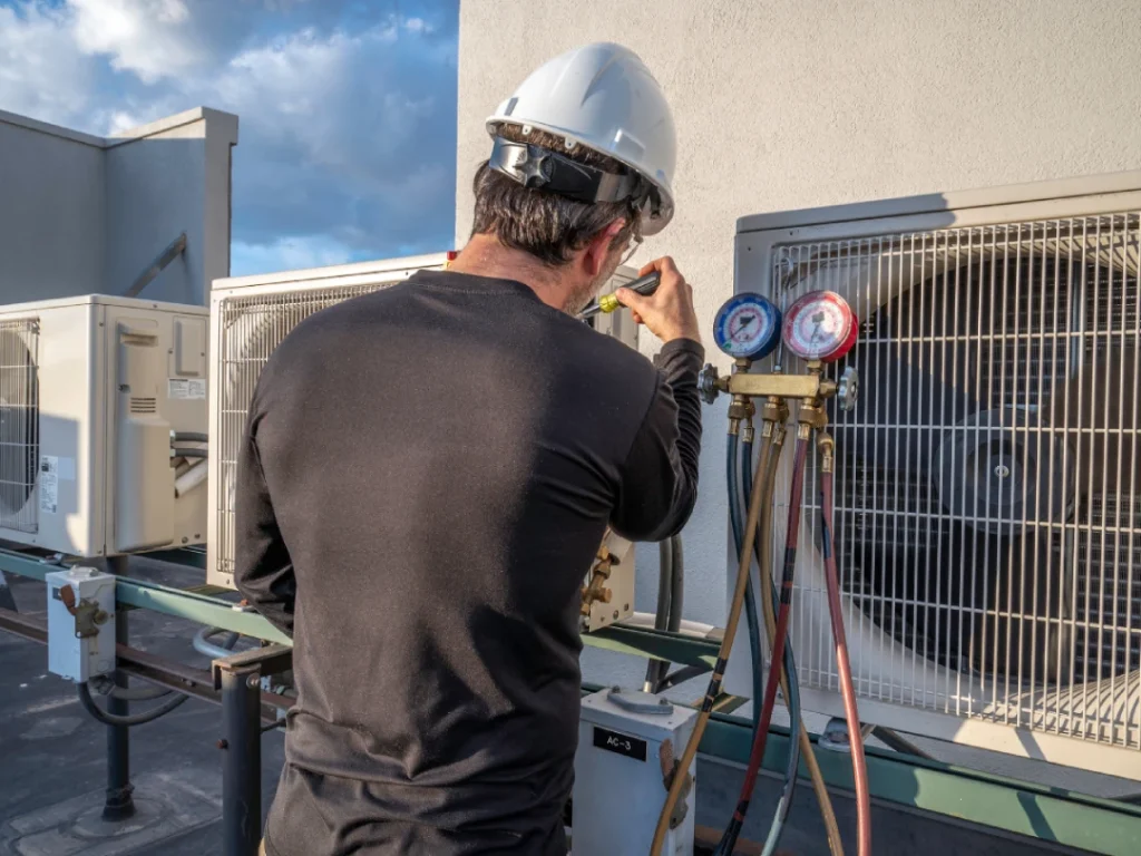HVAC technician checking gauges on outdoor AC unit for fast air conditioner repair in Katy, TX.