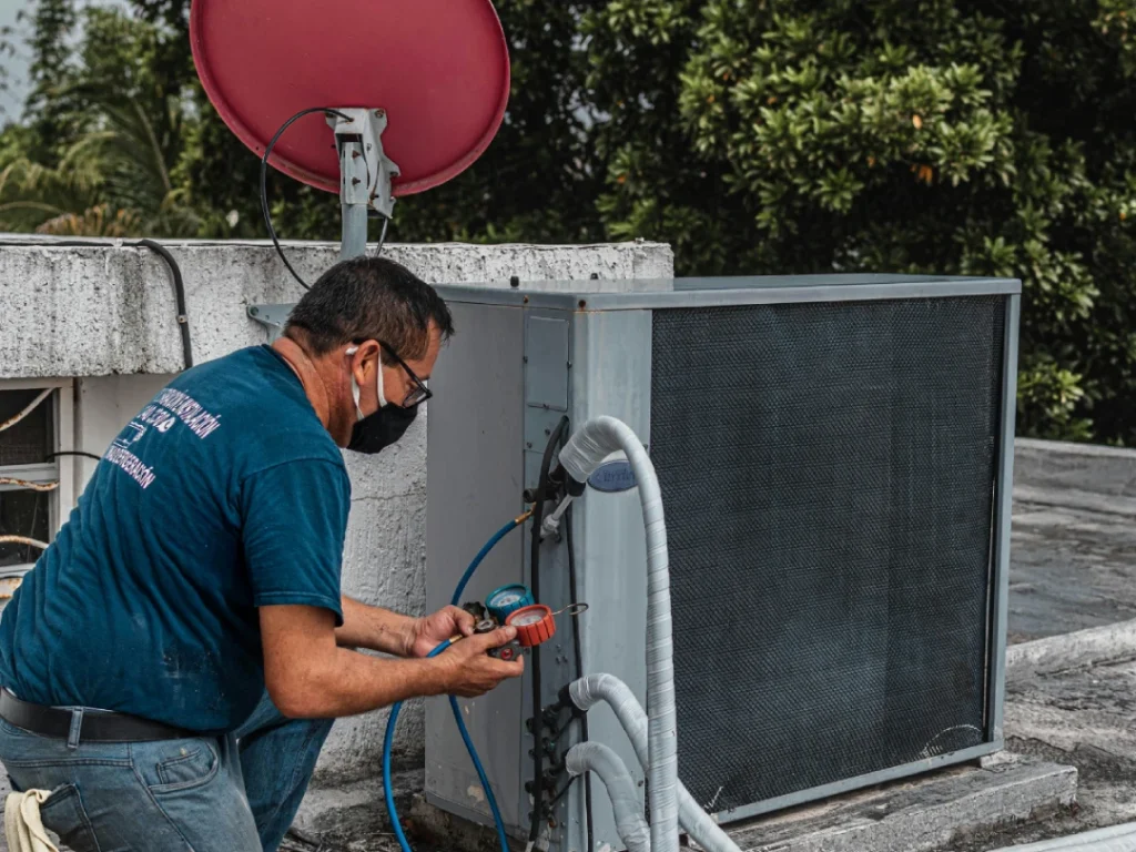 HVAC technician using gauges on rooftop AC unit for free estimates for AC repair in Katy, TX.