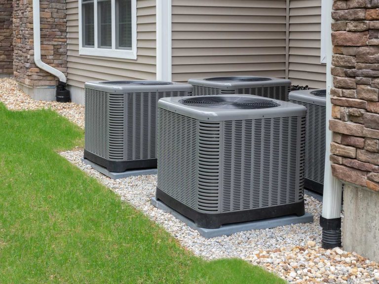 Multiple AC units outside a home needing emergency AC repair in Katy TX, surrounded by gravel and lush green grass.