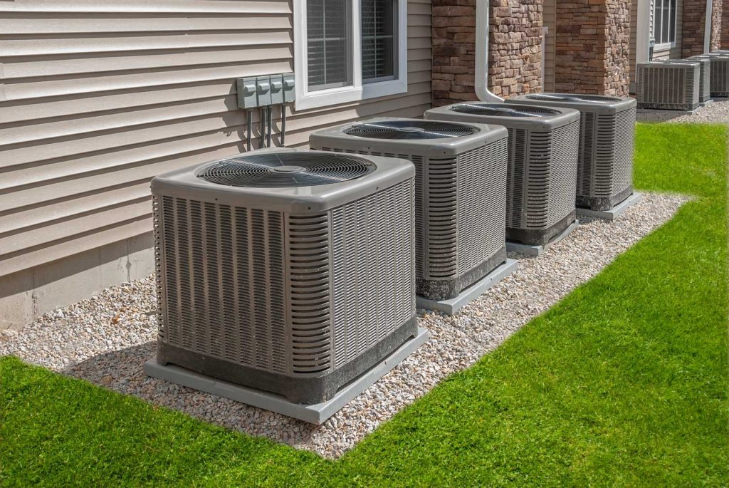 Outdoor view of several AC units needing emergency AC repair in Katy TX, set against a well-maintained lawn and home exterior.