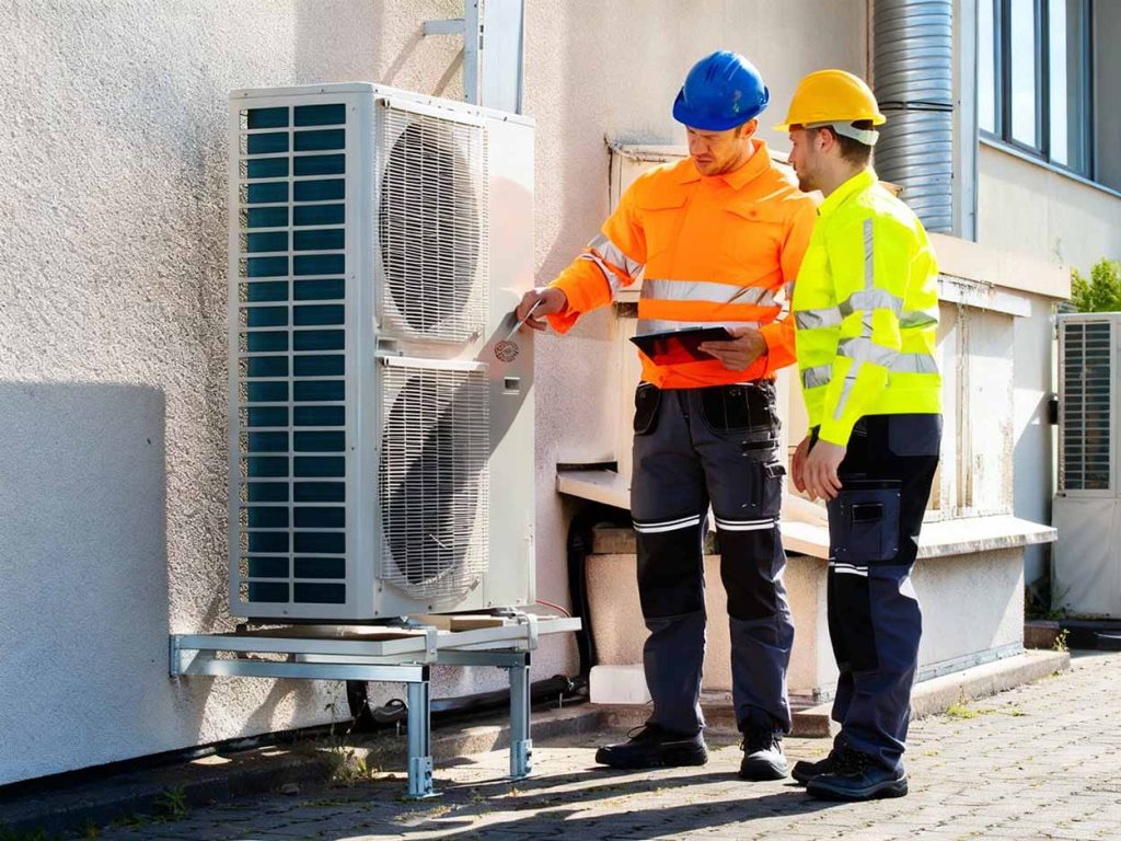 Annual air conditioner tune-up Katy – two techs inspecting system to prevent summer breakdowns
