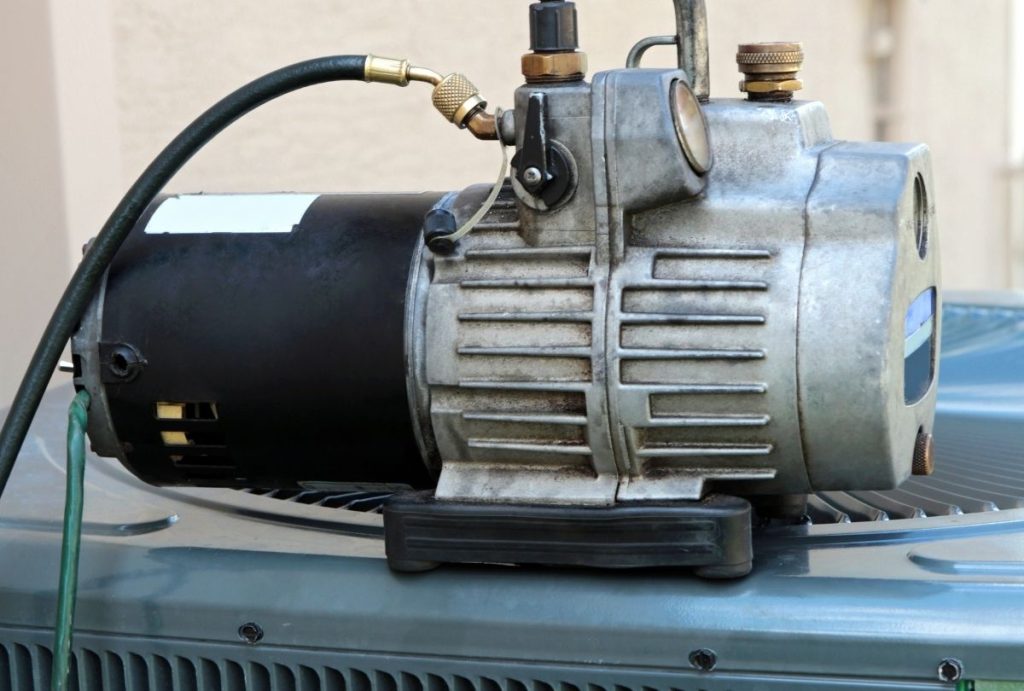 Close view of refrigerant recovery pump connected for thorough air conditioner tune-up in Katy TX, promoting energy savings and longevity.