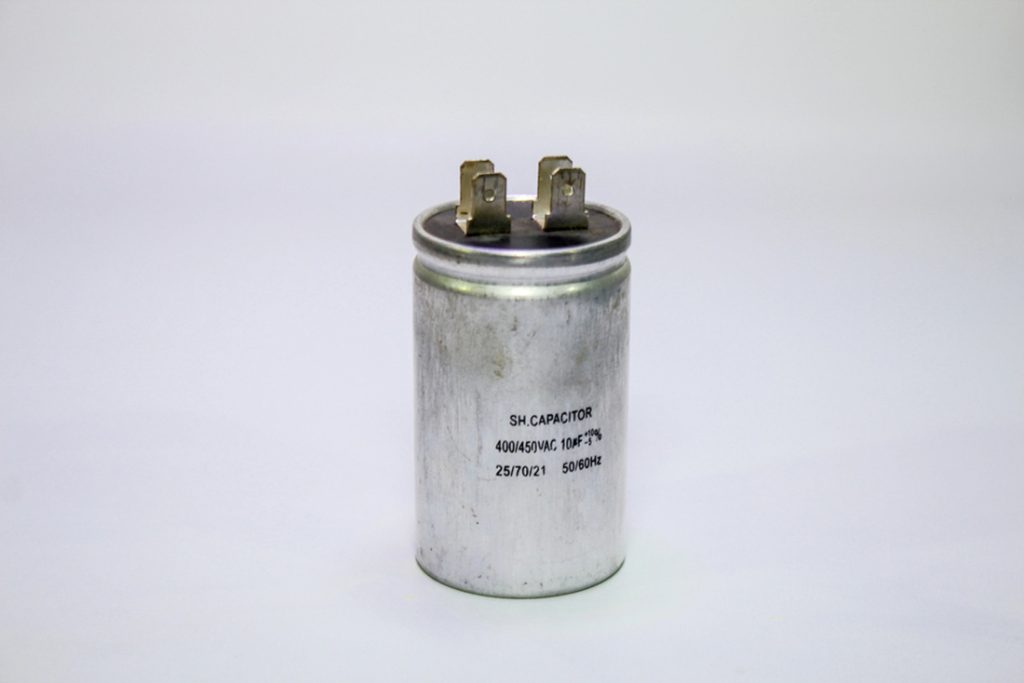 Close-up of a cylindrical SH run capacitor rated 400/450VAC 10µF for air conditioner replacement in Katy TX, showing dual terminals on white background.