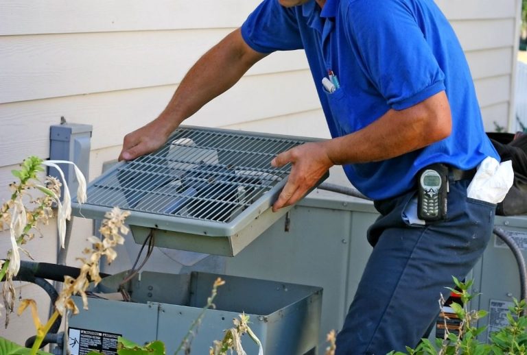 HVAC specialist removing condenser cover during professional air conditioner tune-up in Katy TX, ensuring system efficiency and reliability.