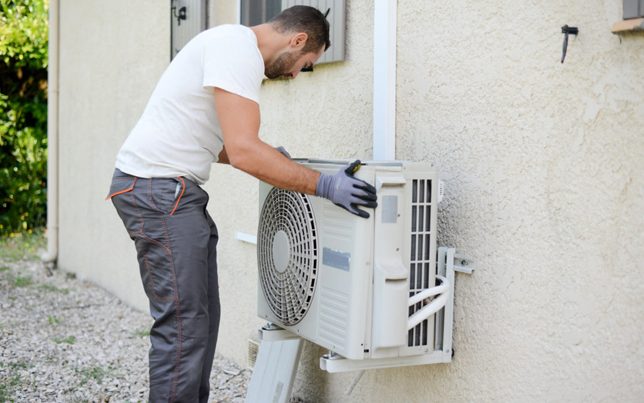 Professional crew member finishing an ac installation fulshear tx by mounting an outdoor unit to a home exterior.