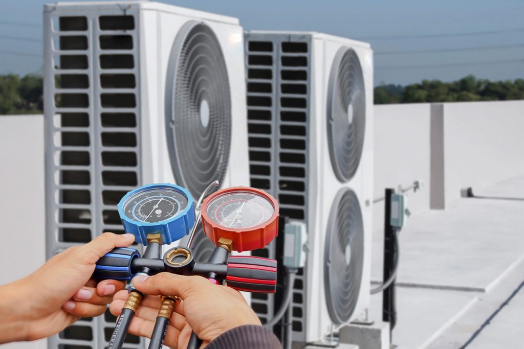 Technician holds essential manifold gauges to measure refrigerant pressure, a key step for diagnosing failures during an Emergency AC repair Katy TX.