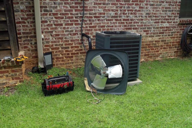 AC condenser unit with the fan blade and top cover removed on the lawn. Trustworthy AC repair Cinco Ranch services.