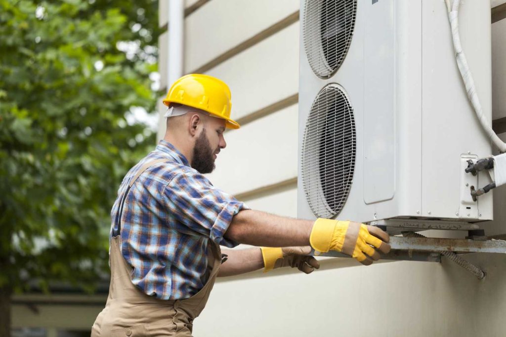 Professional technician providing affordable AC repair Katy TX services on a building's outdoor condenser unit. 