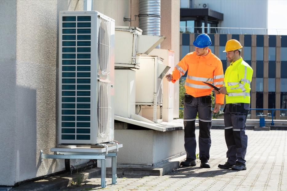 Technicians from the best AC repair company in Katy TX inspect an outdoor commercial condenser unit on a roof.