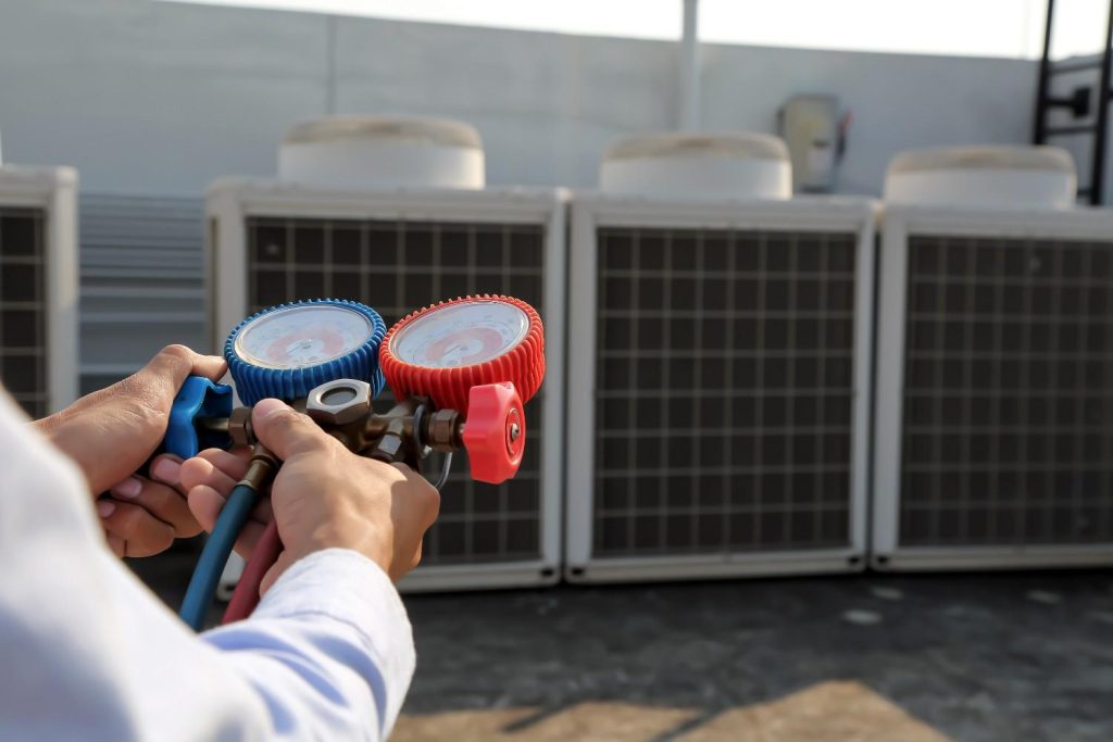 Close-up of a technician holding pressure gauges on a rooftop before giving a free quote AC repair Katy TX estimate. 