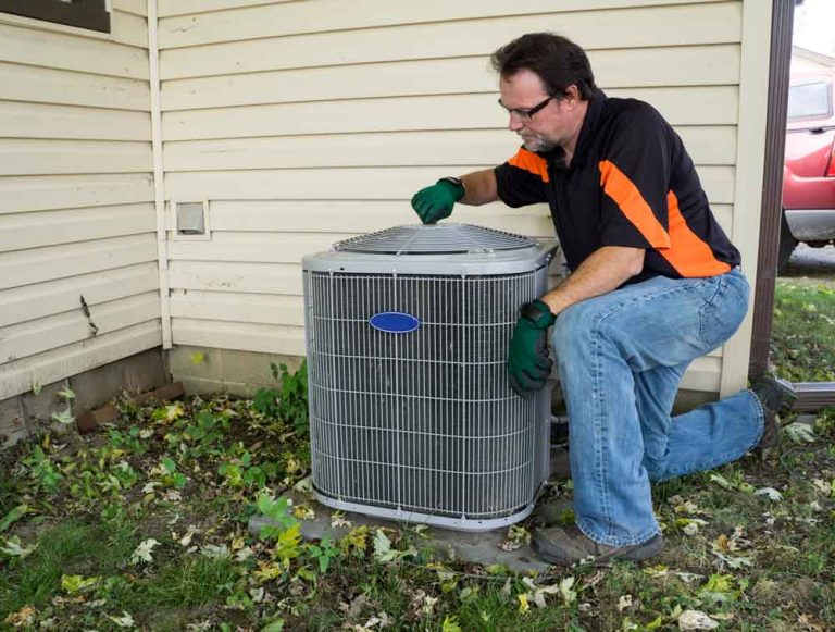 Professional local AC service Katy TX technician inspecting a home outdoor condenser unit in the yard.