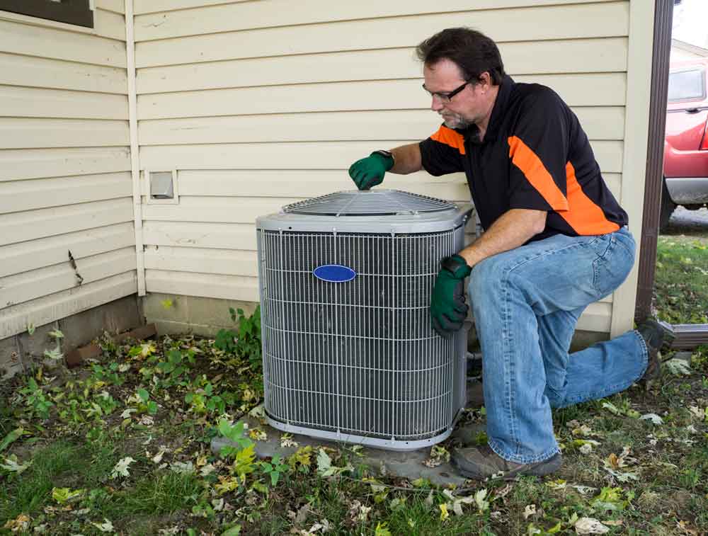 Professional local AC service Katy TX technician inspecting a home outdoor condenser unit in the yard.